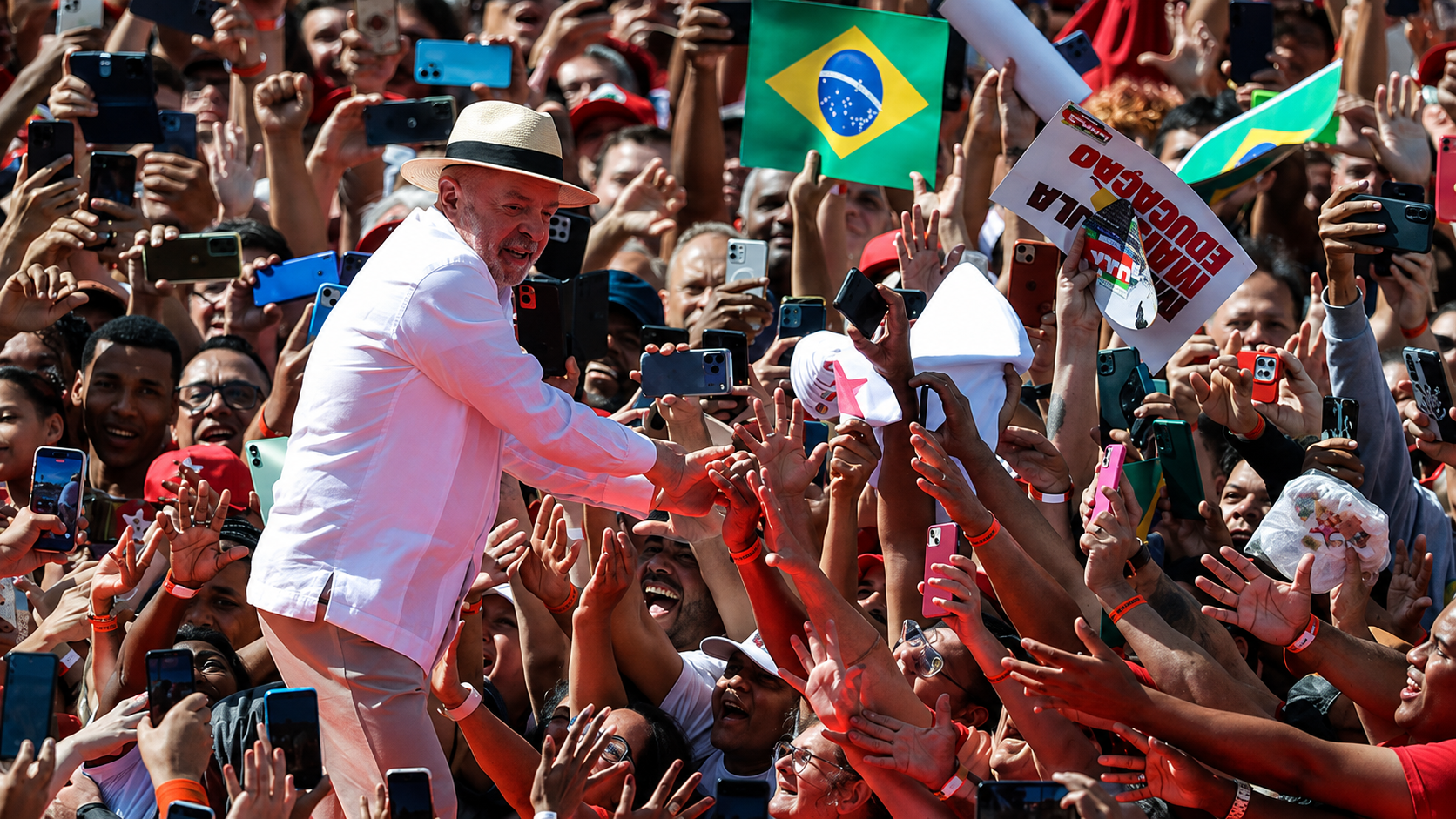 Lula saluda a una multitud que lo graba con teléfonos y ondea banderas de Brasil en un acto de campaña